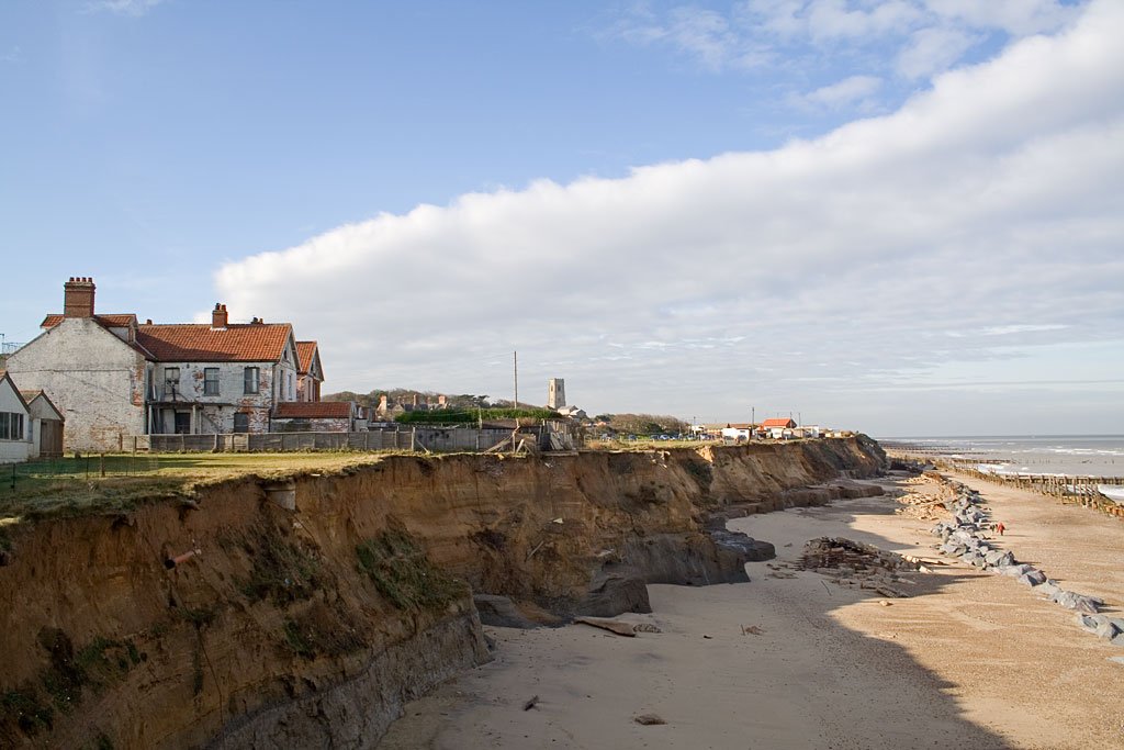 Coastal erosion at Happisburgh, Norfolk, showing severely eroded soft cliffs close to houses and other buildings.