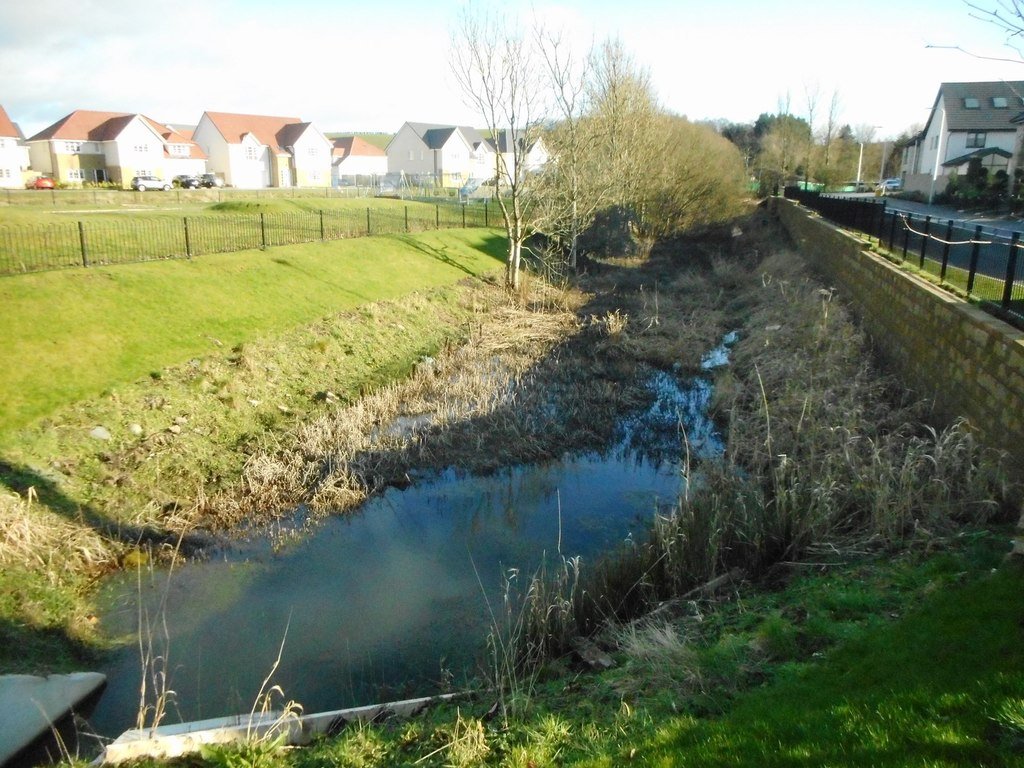Sustainable drainage pond at Kilmardinny Gait, with a vegetated basin beside a residential development collecting and managing surface water.